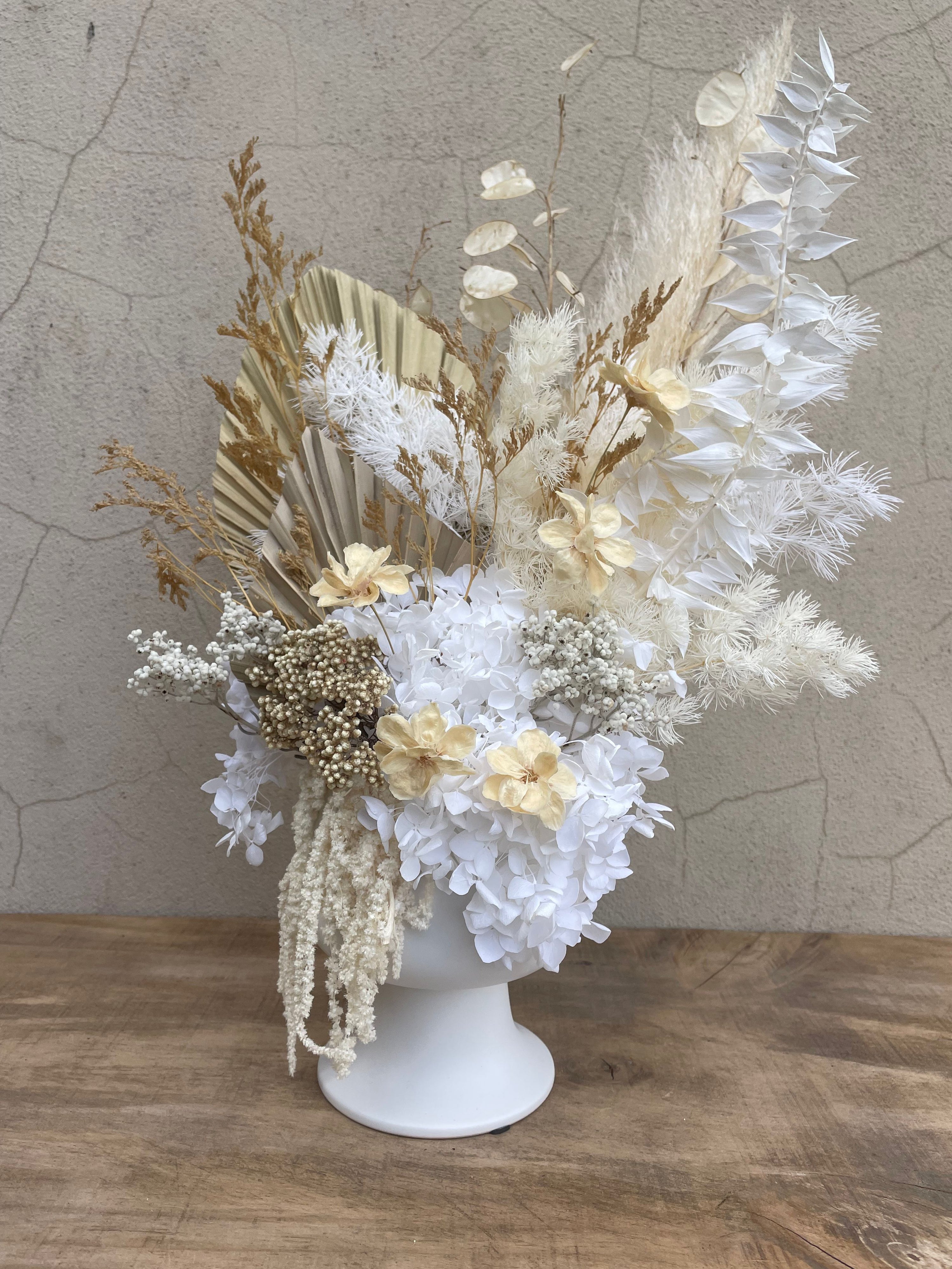 Decorative floral arrangement with dried flowers on a textured surface. Ivory and gold dried floral arrangement in white ceramic vase – The Flower Boutique Perth