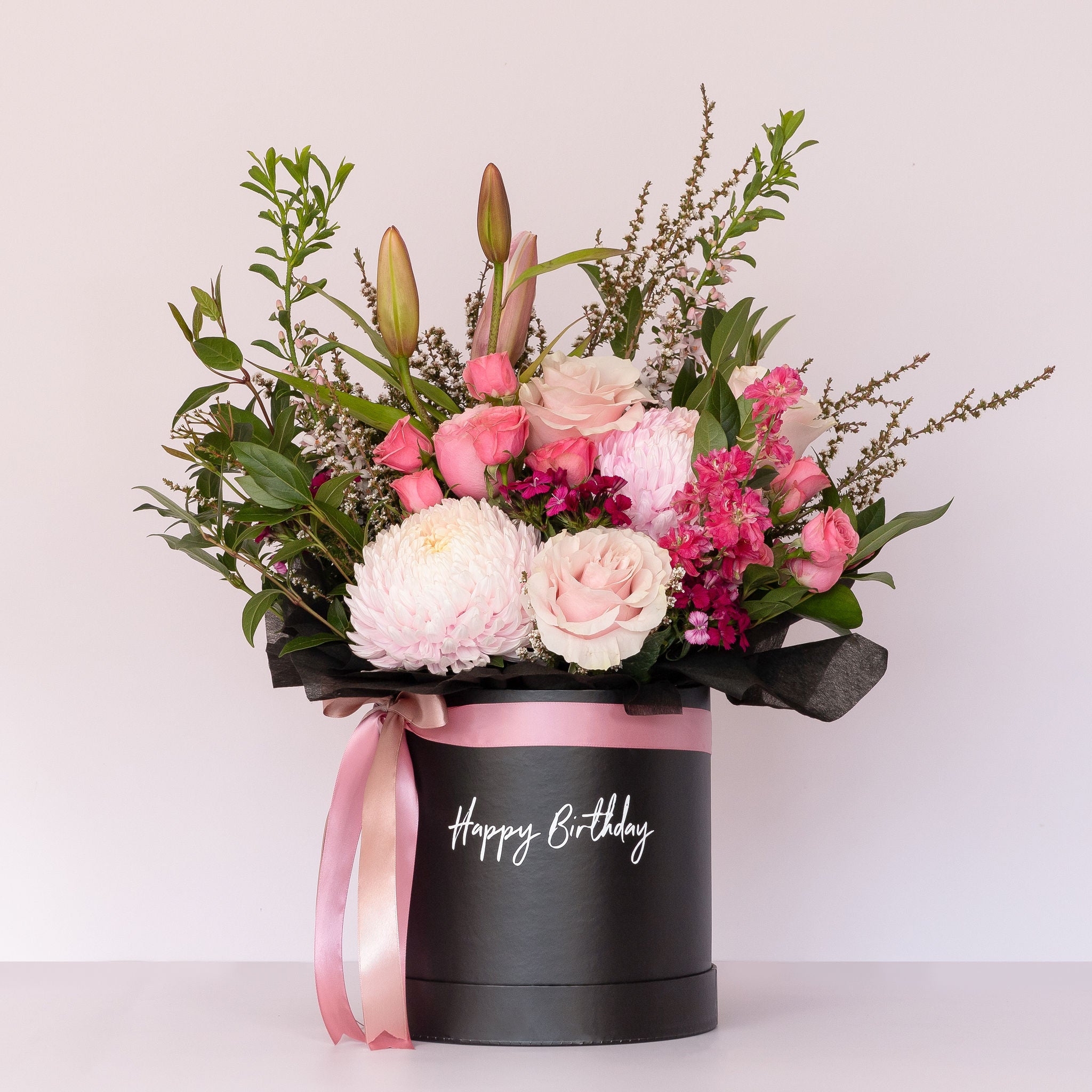 A flower box with blush pink premium blooms arranged in a black keepsake hat box with the message "happy birthday" printed on the front of the box. Available for delivery across Perth or pick up from our Ashby store The Flower Boutique