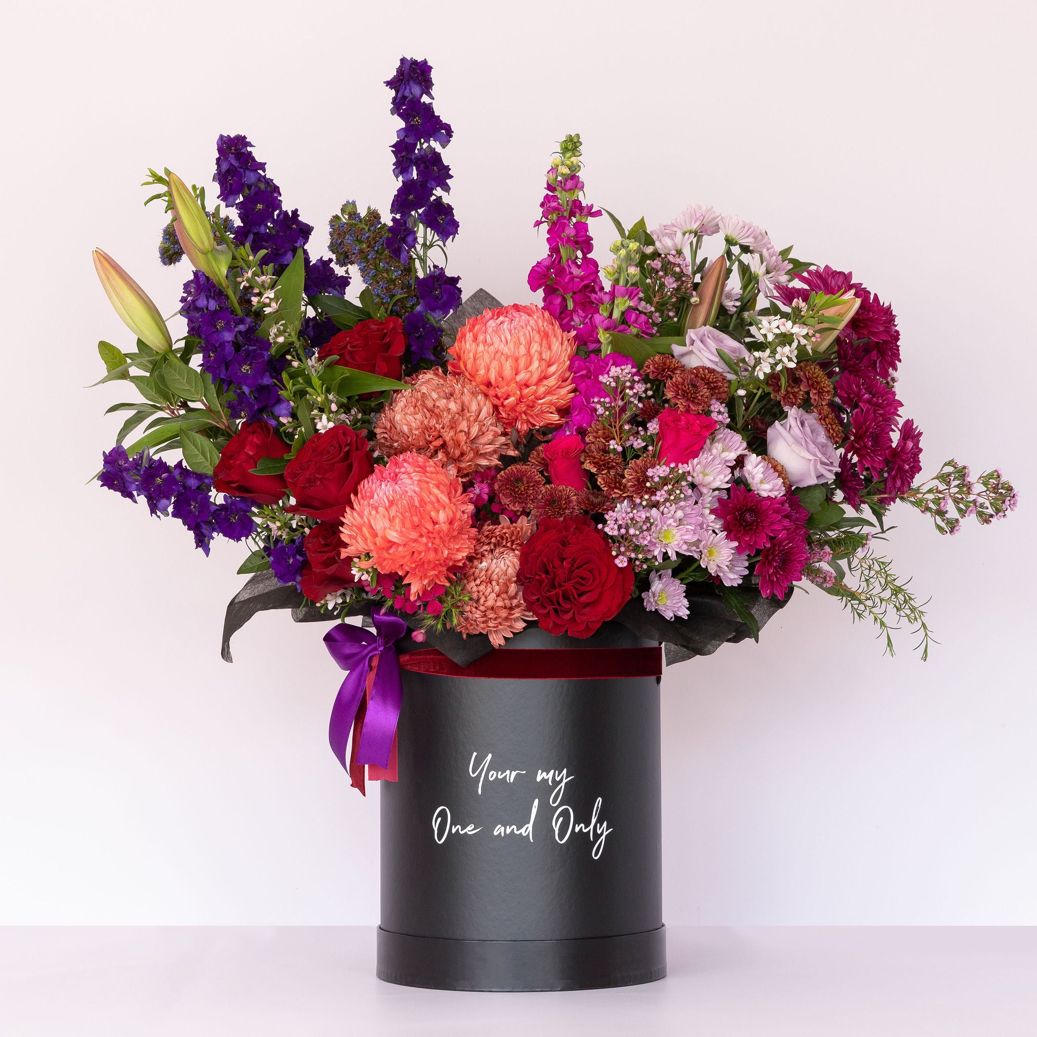 "A lavish black keepsake box containing bold and berry-toned blooms with the message 'You're My One And Only' written on it."