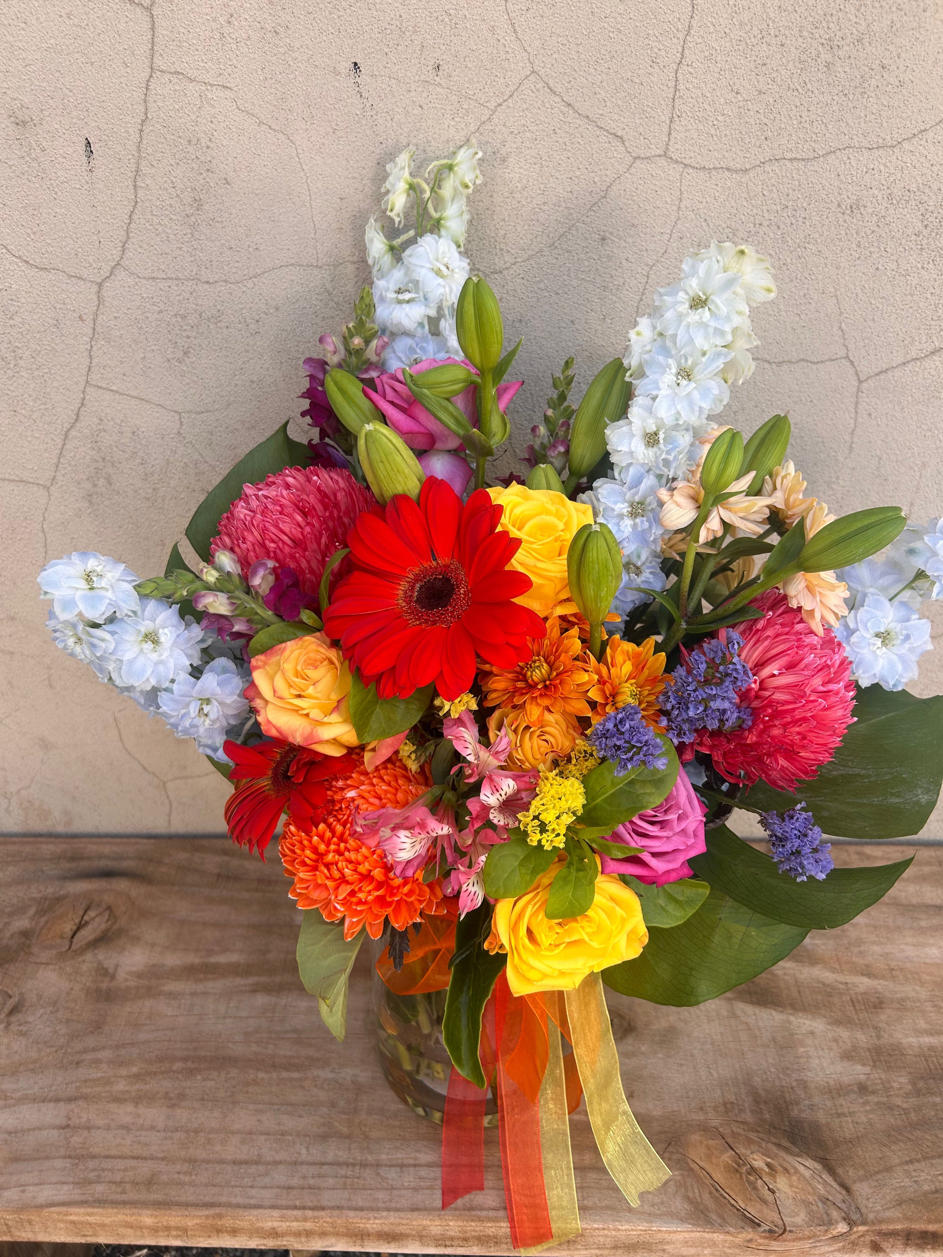 Close-up of Elysian Garden floral arrangement showing vibrant roses, textured chrysanthemums and layered seasonal blooms in glass vase