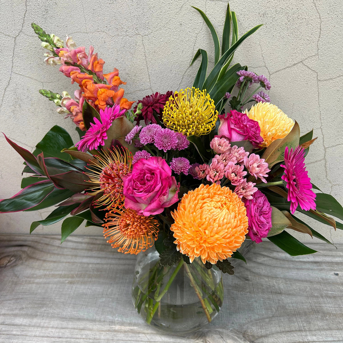 Festa Floreale vase arrangement viewed from above, showing pink roses, orange and yellow flowers with greenery