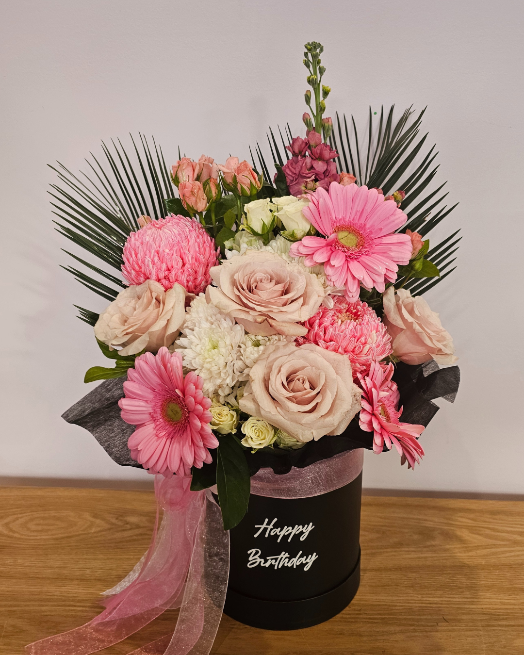  Deluxe blush pink flower box in a black keepsake hatbox with “Happy Birthday” written in elegant script, perfect for birthday celebrations.