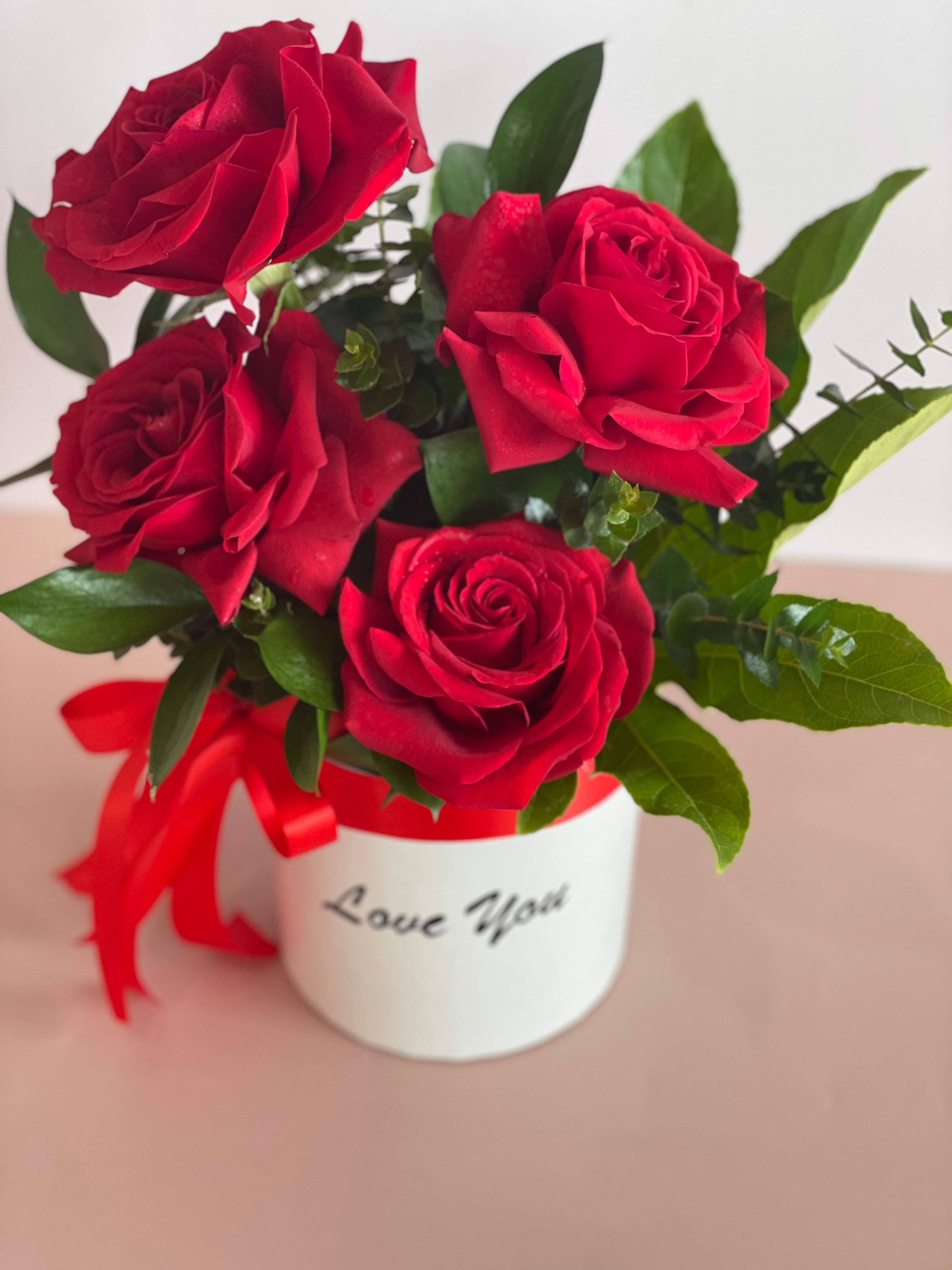 VIDA flower box with a lovely red ribbon and bright green folliage featuring four beautiful premium Ecuadorian roses in a white keepsake box.