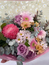 Mother’s Day flower bouquet featuring pink chrysanthemums, lavender roses, white daisies, and soft greenery wrapped in pink paper with daisy-print backing — The Flower Boutique Perth