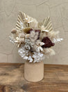 Dried floral arrangement with preserved roses, white hydrangeas, palm spears, and textured fillers in a stone ceramic vase.