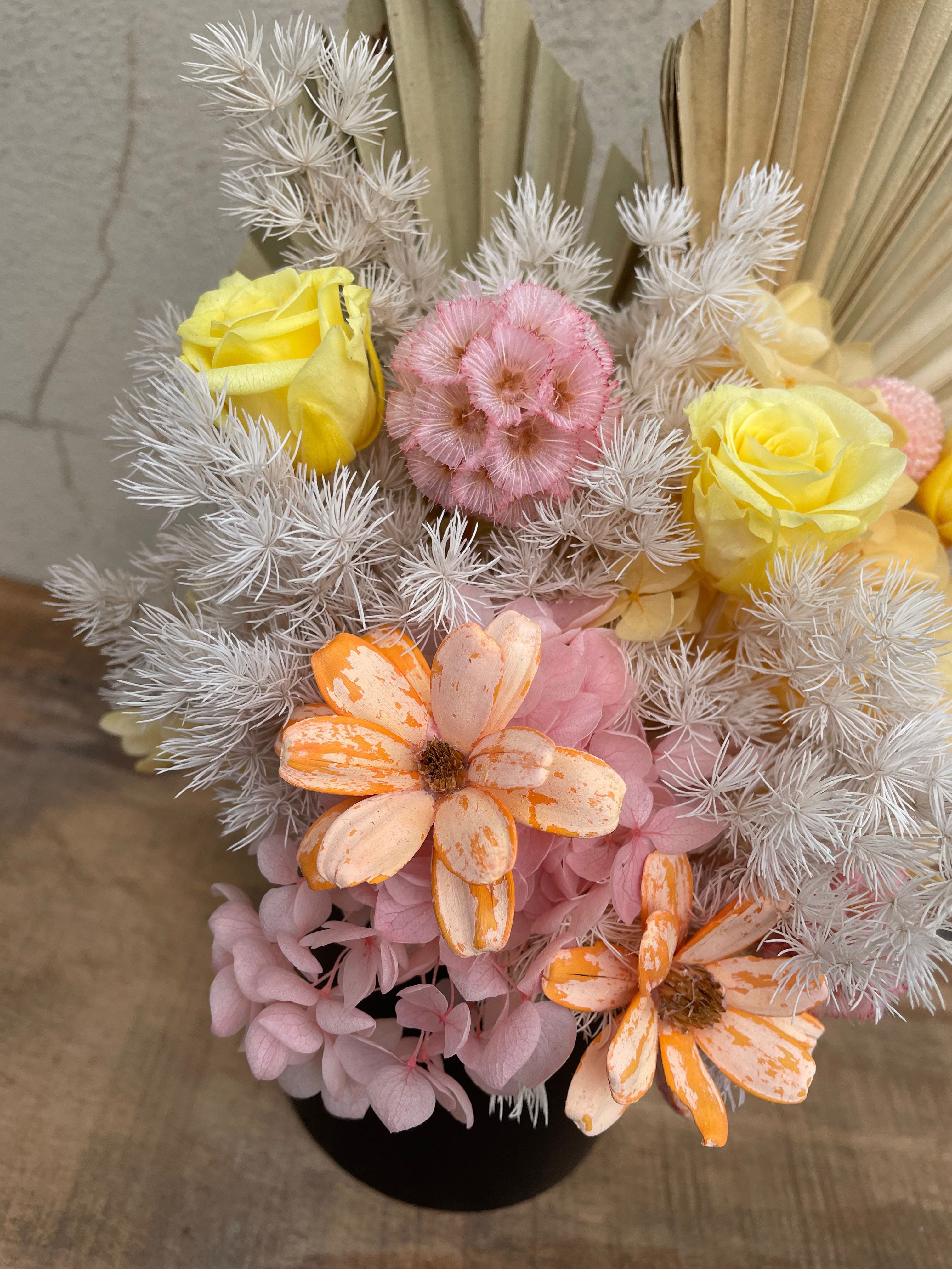 Bouquet of flowers with pink, orange, and yellow colors on a textured surface.