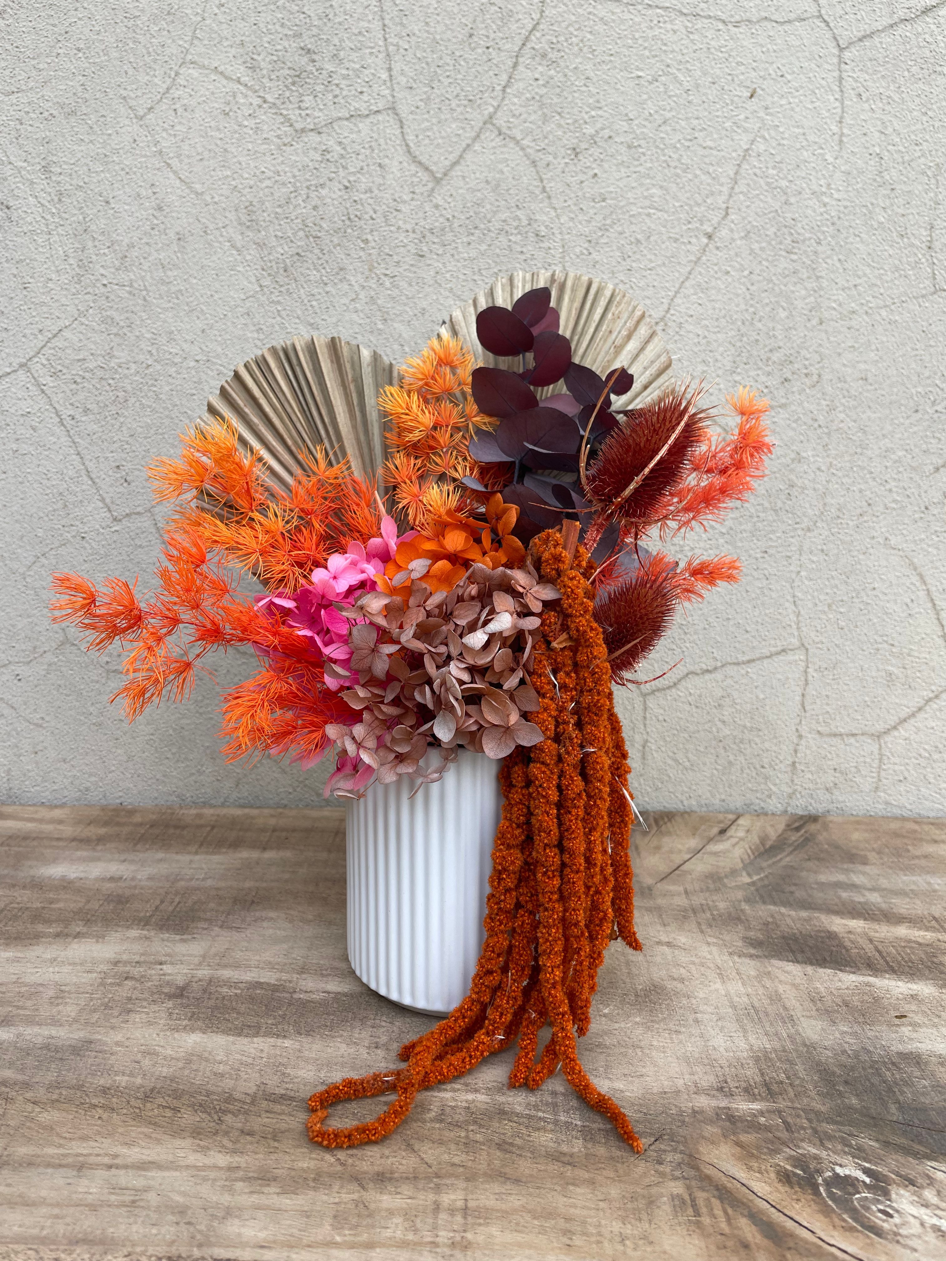 Decorativedried floral arrangement with orange, brown and and burnt textures with a touch of pink flowers in a white ceramic vase. Available for same day flower delivery Perth from The Flower Boutique