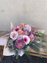 Bouquet of pastel pink tones, fresh flowers on a wooden board with a concrete floor background available for same day delivery accross perth