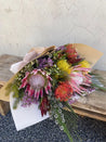 Wild Flowers wrapped in a bouquet sitting on a wooden chair ready for pick up from The Flower Boutique Perth