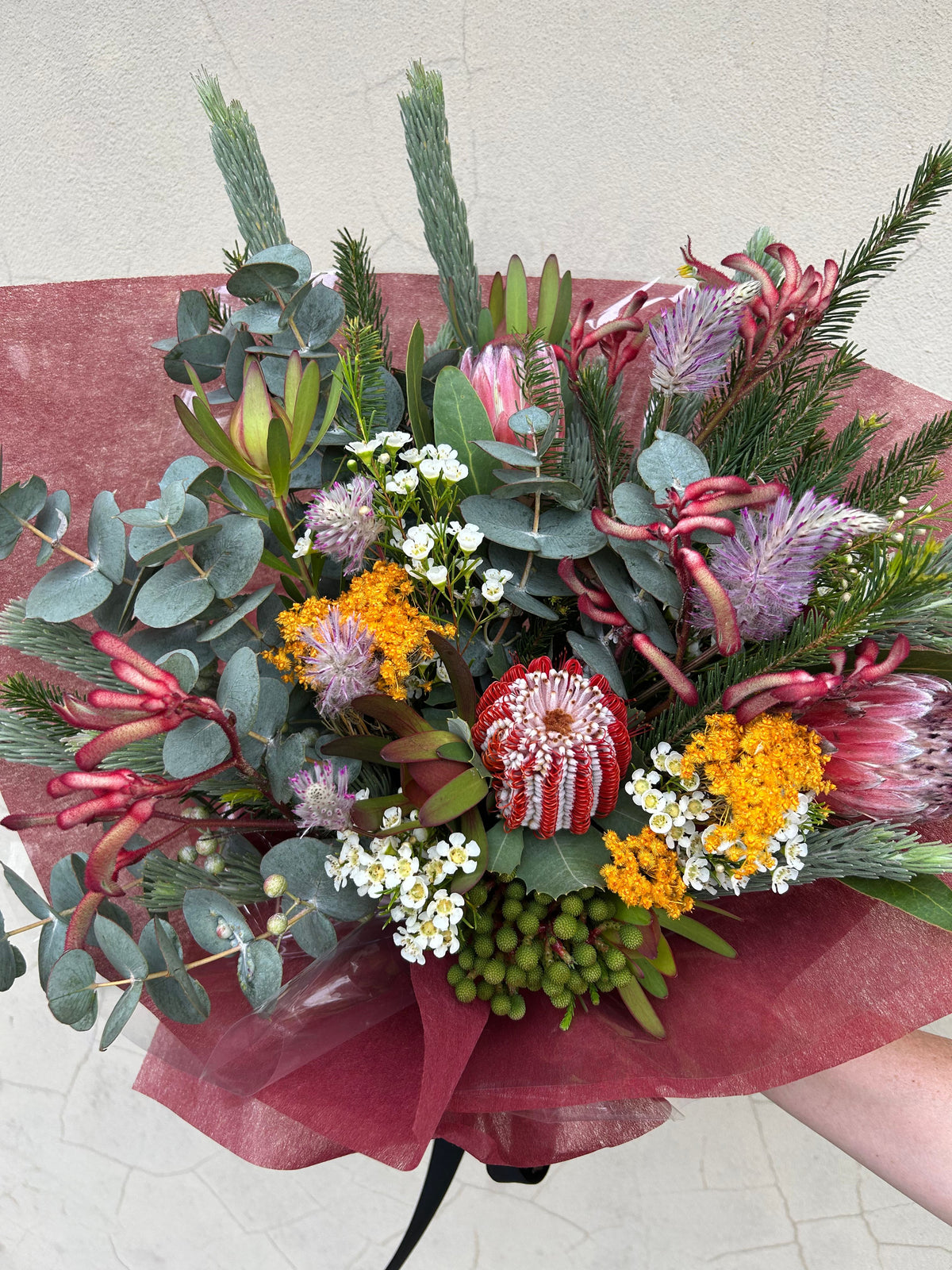 1. Native Instinct bouquet viewed from above, showing pink proteas, yellow flowers and green foliage