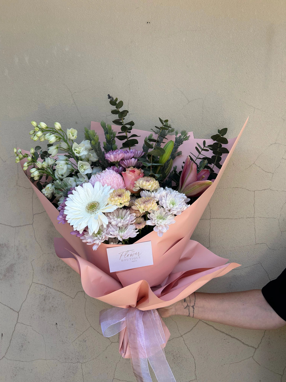 Deluxe Pink Blossom Delight bouquet with pink, cream and lilac flowers, held in pink wrapping with ribbon