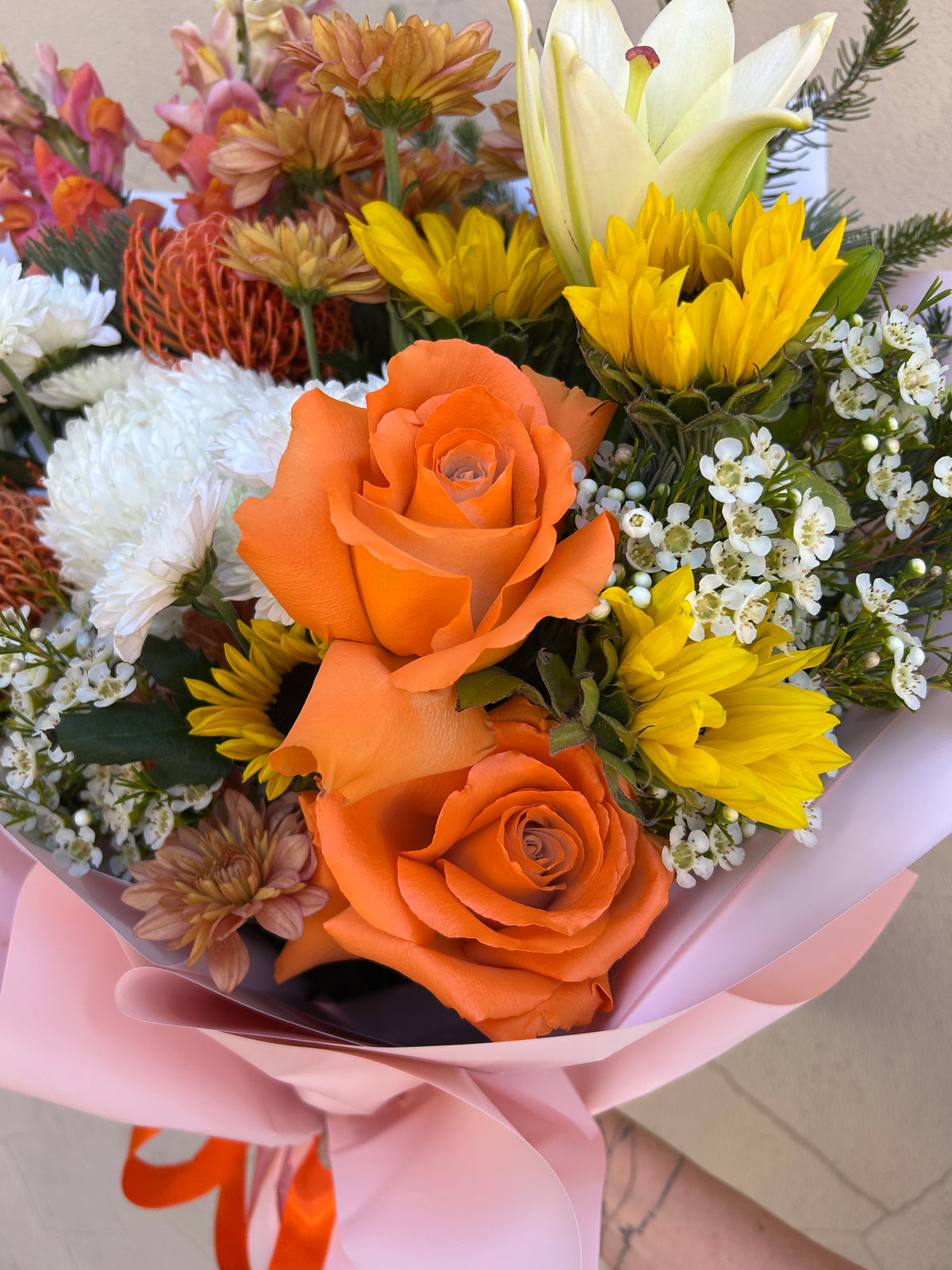 Close-up of orange roses and yellow flowers in the Hello Spring bouquet