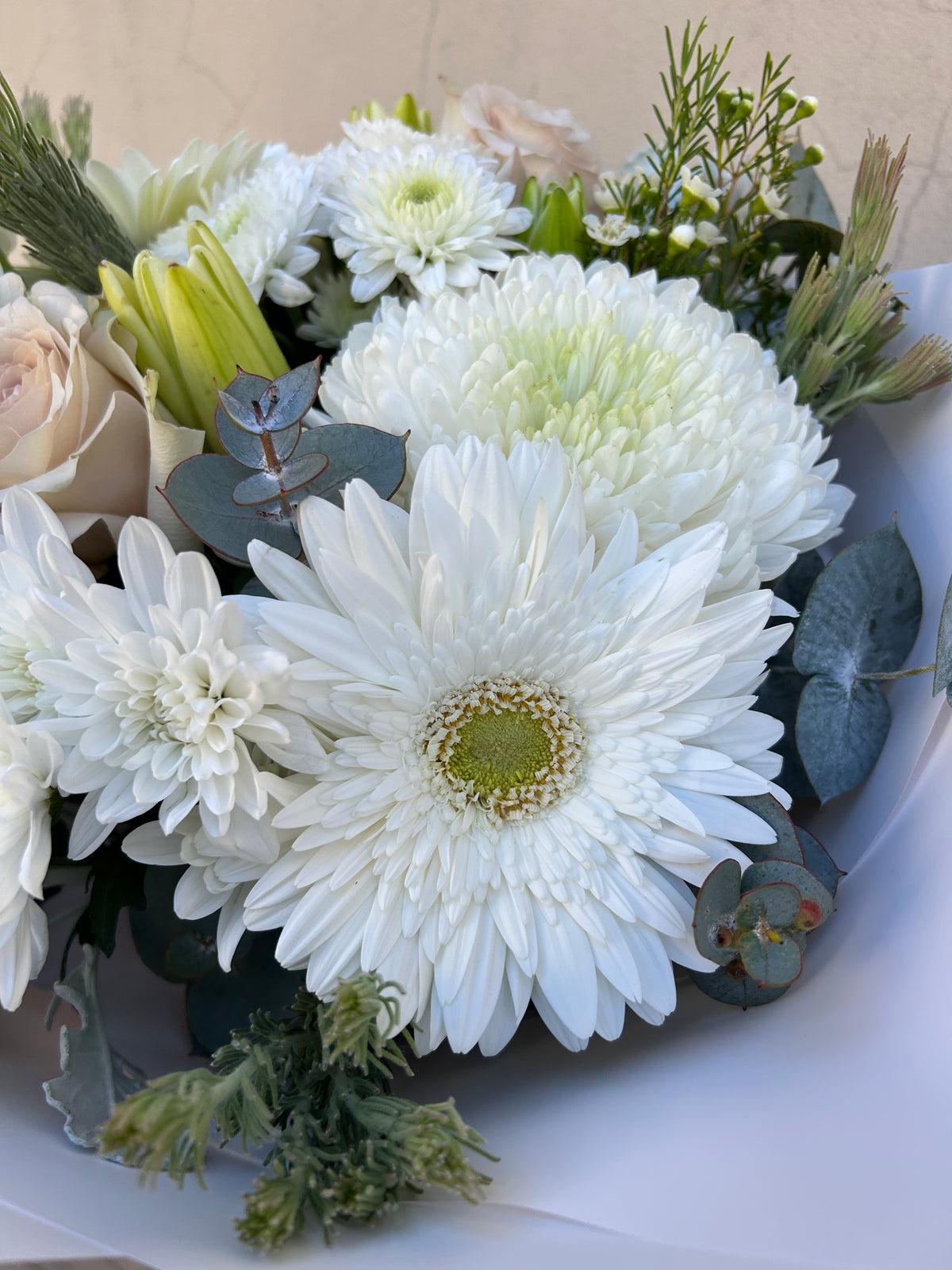 Close-up of white chrysanthemums and greenery in the Simplicity bouquet