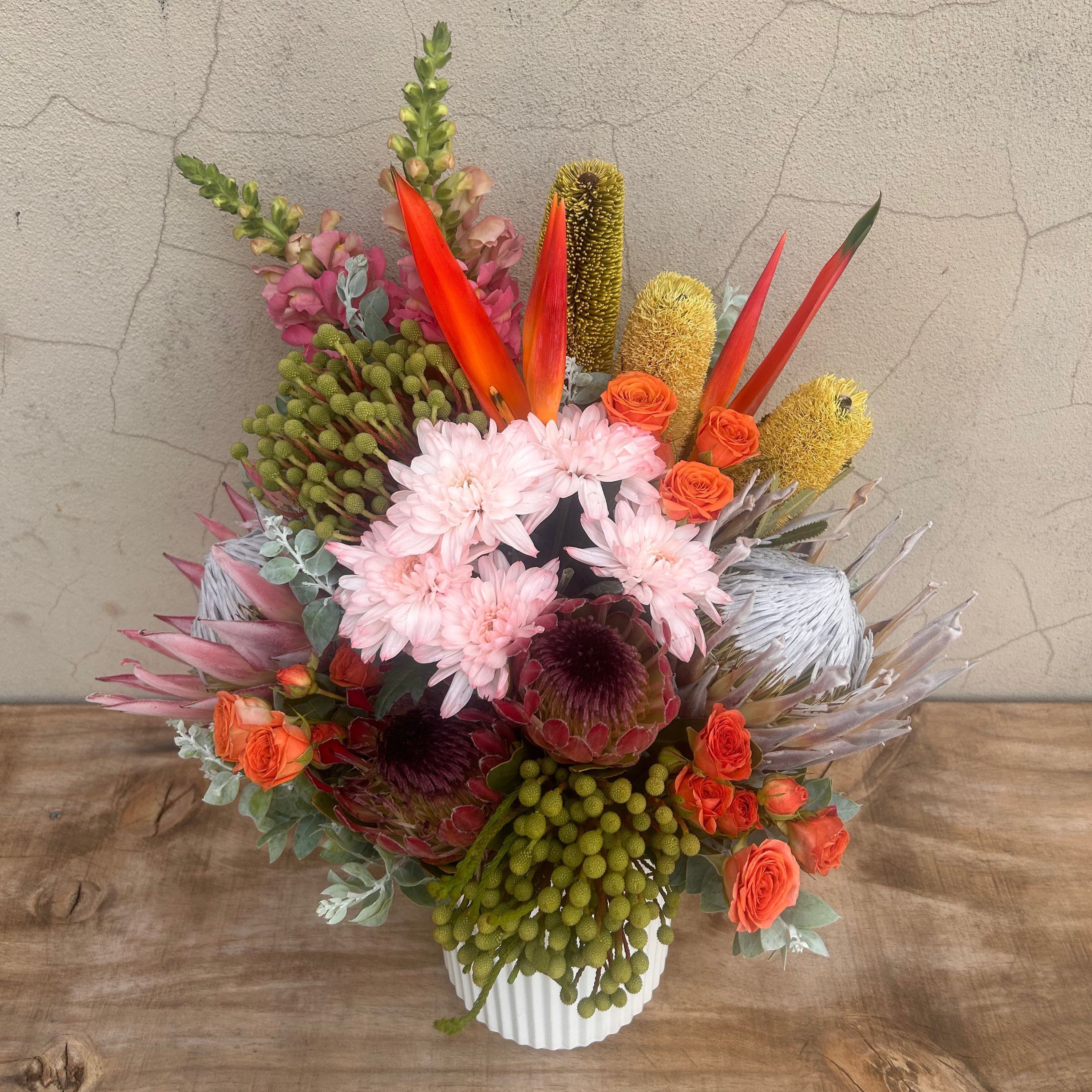 Proteas, banksias and blush mums in elegant Marabella Vase by The Flower Boutique