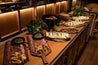 Wooden counter with various food items and a plant in a restaurant setting