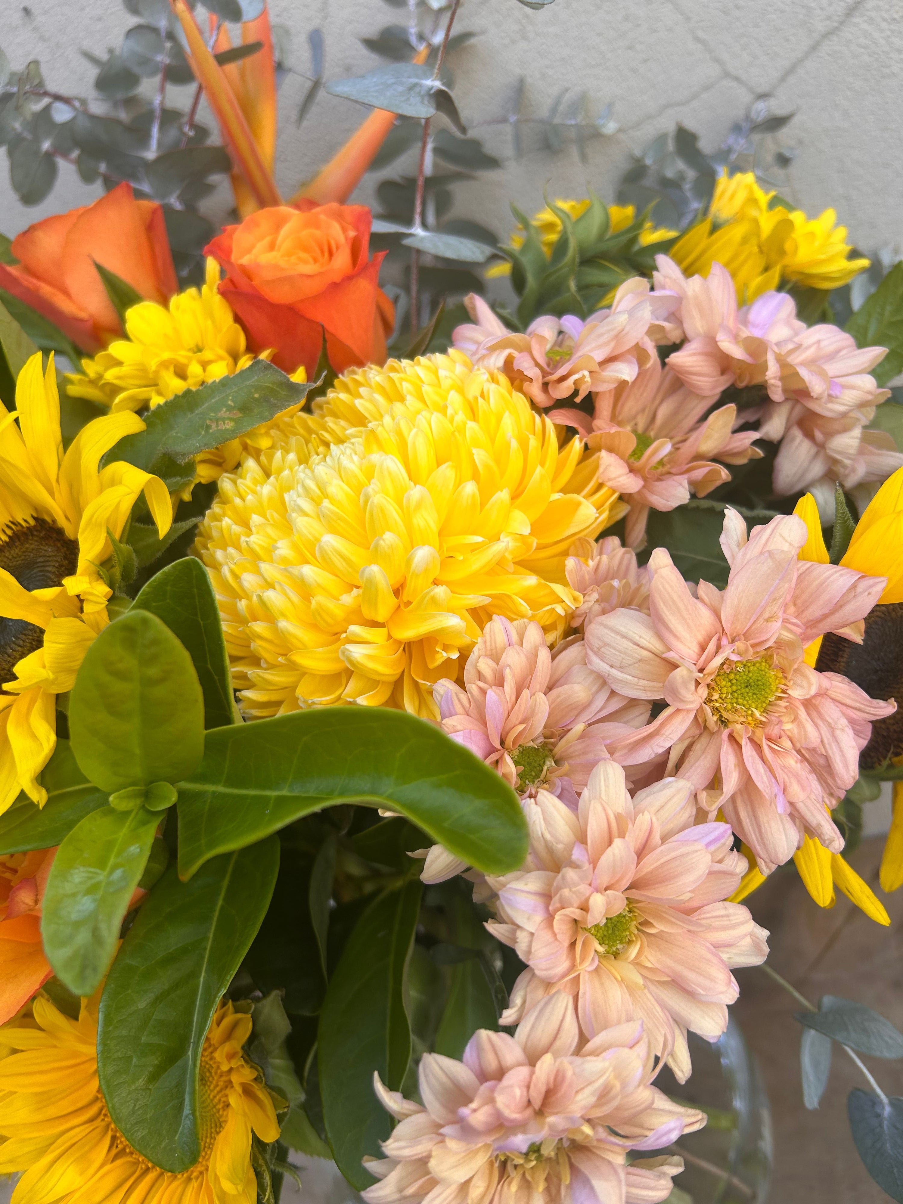Bright sunflower bouquet in clear glass vase with yellow and orange tones