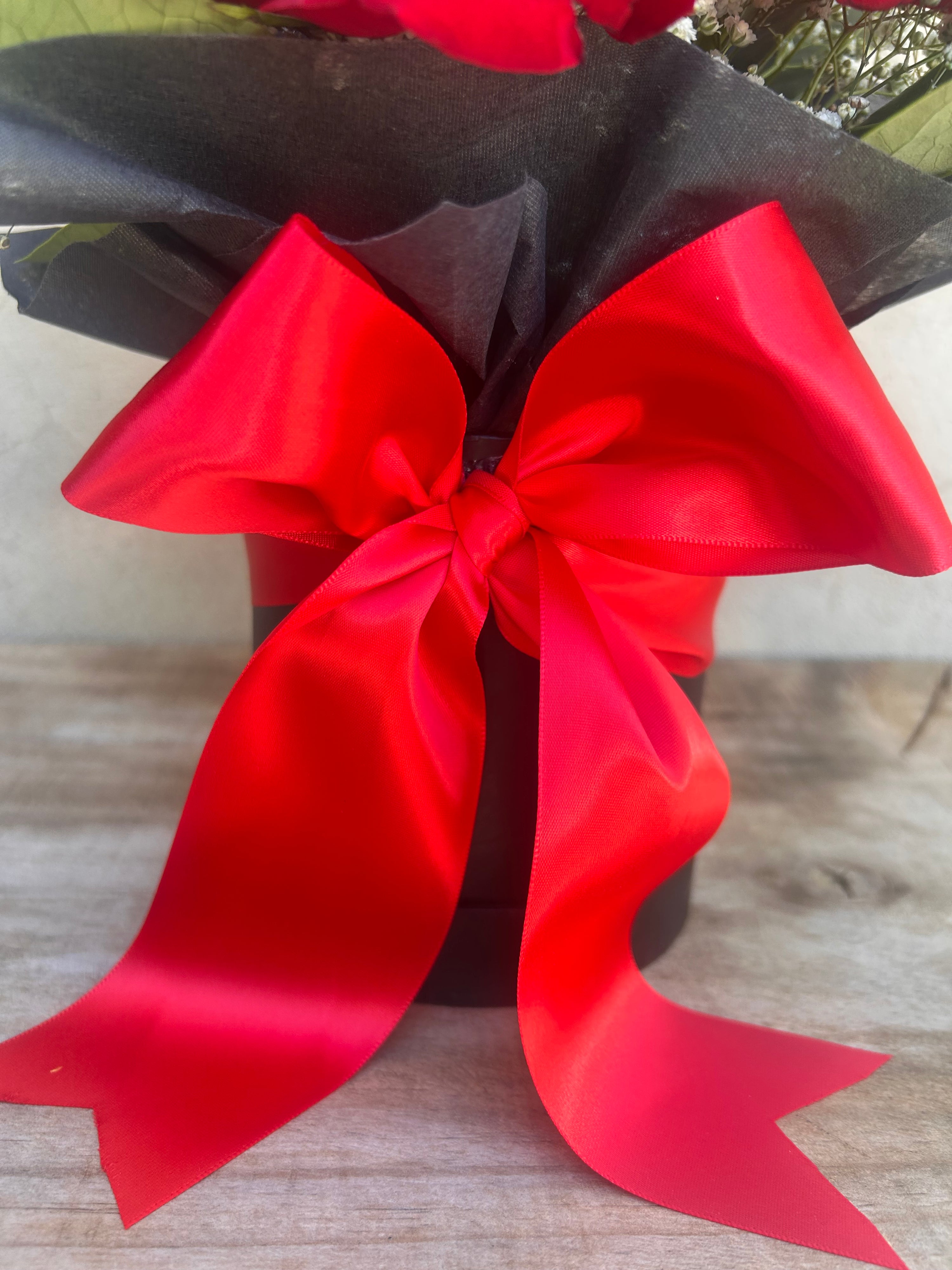 Red bow on a black background with a wooden surface