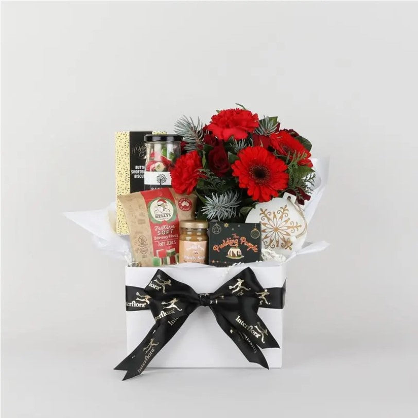 Gift basket with red flowers, snacks, and a black bow on a white background. The perfect Christmas themed gift box or hamper to send accross Perth